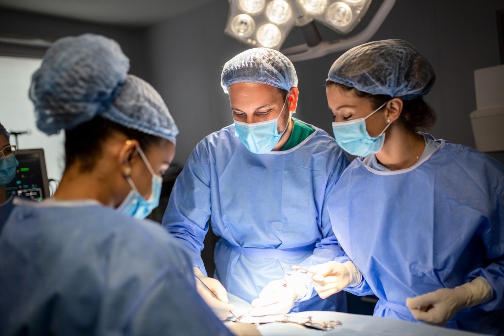 Group of surgeons doing surgery in hospital operating theater. Medical team doing critical operation. Group of surgeons in operating room with surgery equipment. Modern medical background