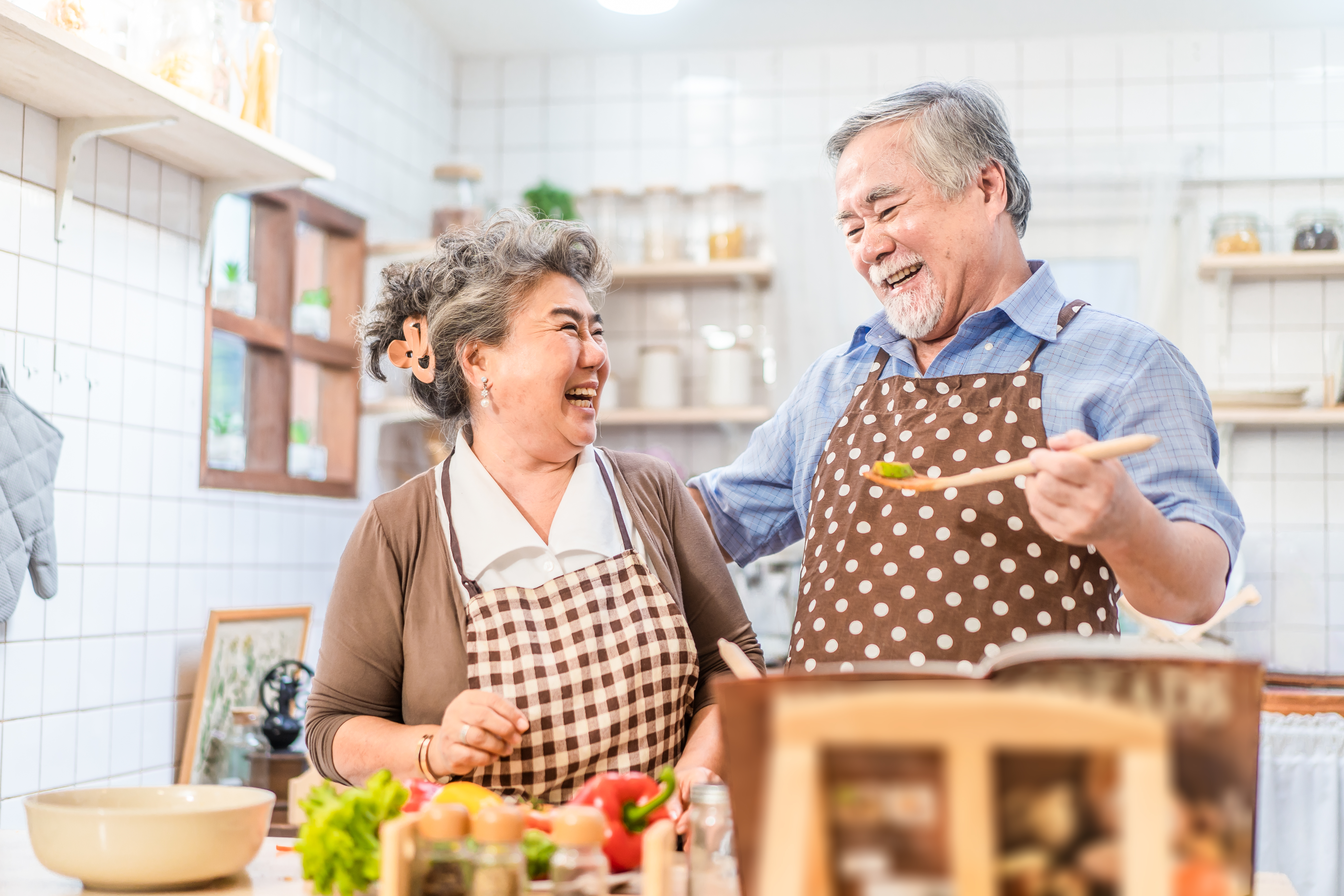 Couple senior Asian elder happy living in home kitchen. Grandfather cooking salad dish with grandmother with happiness and smile enjoy retirement life together. Older people relationship and lifestyle